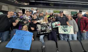 Group of enthusiastic hockey fans at a game holding supportive signs for Zoe and the Sirens team