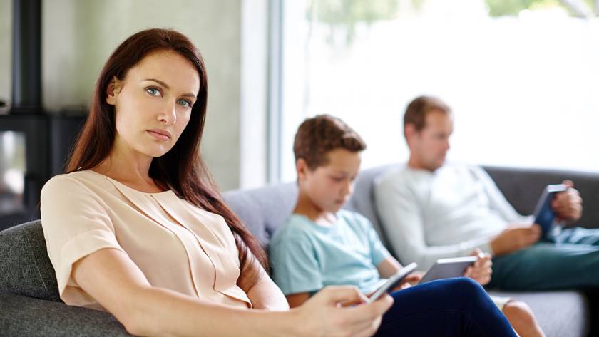 Woman sitting on a couch with two people using tablets and smartphones in a modern living room