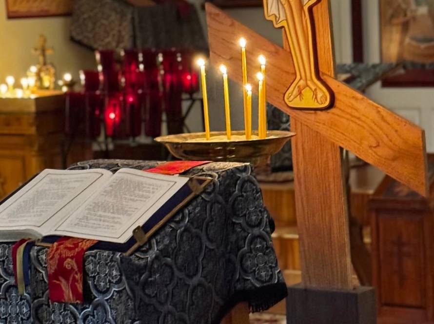 Open Bible with lit candles and wooden cross in a dimly lit church setting, creating a spiritual ambiance