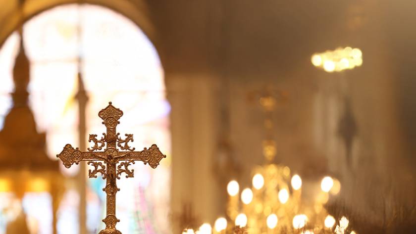 Golden ornate cross inside a church with blurred background and glowing lights