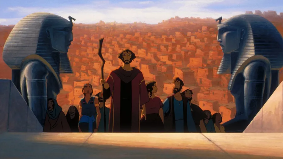 Animated group stands before giant Pharaoh statues in ancient cityscape, holding a staff in a dramatic, historical scene