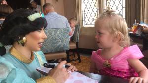 Princess character interaction with young girl in a pink dress at a themed restaurant