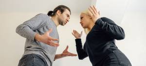 Man and woman in heated argument indoors, body language showing frustration and disagreement