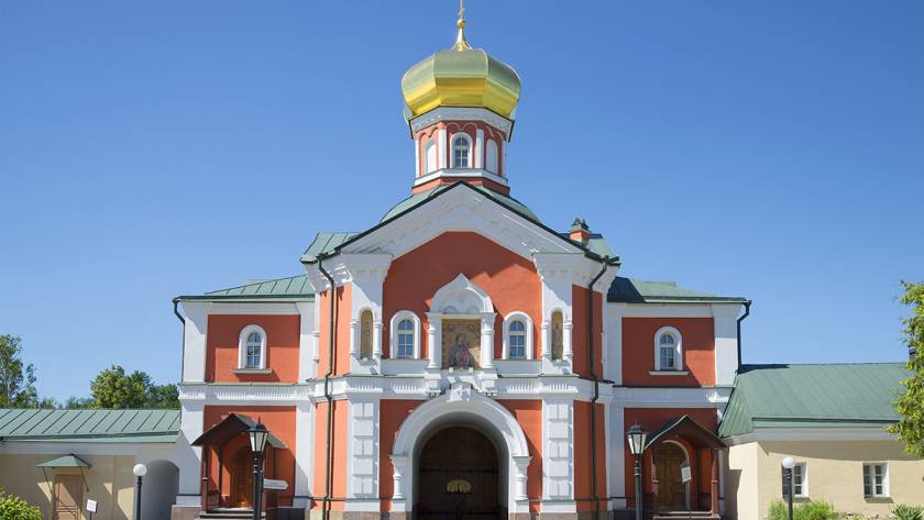 Colorful Orthodox church with golden dome under clear blue sky, showcasing intricate architecture and vibrant design
