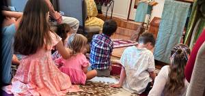 Children sitting on a carpet during a gathering in a cozy room with soft lighting