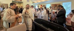 Priests and congregation gather for a baptism ceremony in a church setting