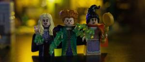 Three witch-themed LEGO minifigures with glowing backgrounds holding green potion elements and a broomstick