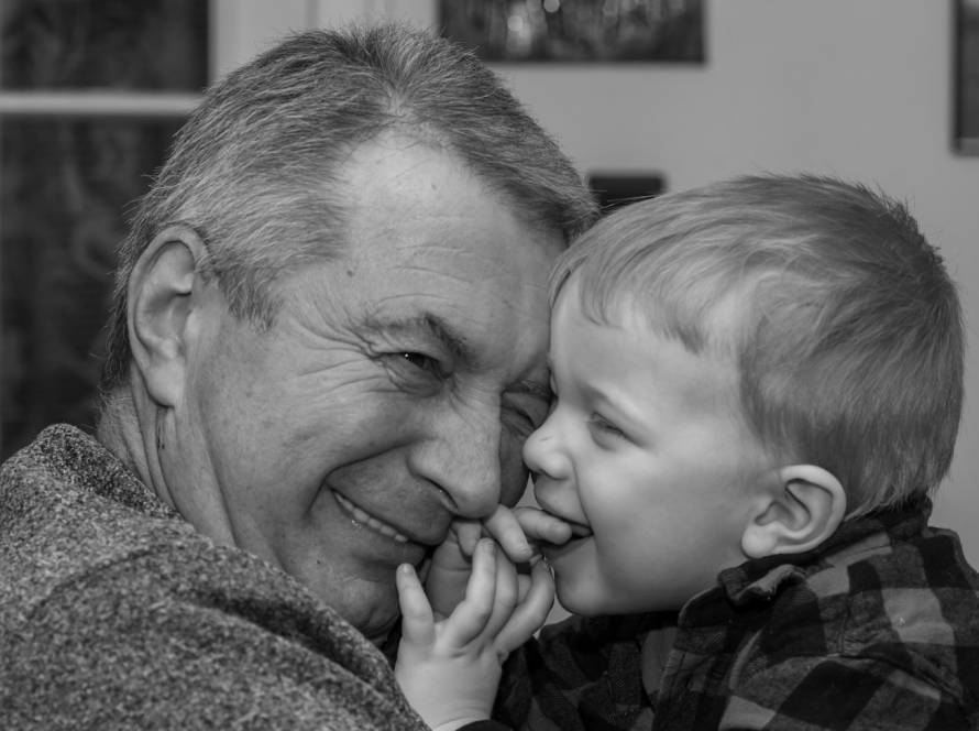 Grandfather and grandson sharing a joyful moment, smiling closely together in a heartwarming black and white photo
